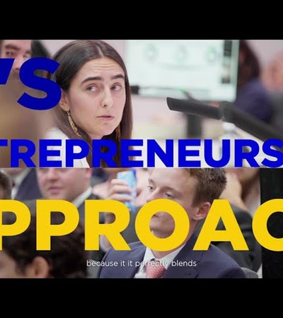 A focused individual in a professional setting surrounded by peers engaged in discussion.