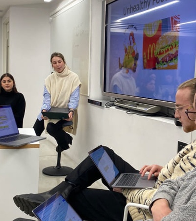 A group of people participating in a workshop about unhealthy food, with a presentation slide displayed in the background.
