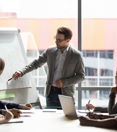 A businessman presents in front of a group during a meeting.