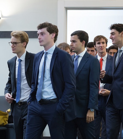 A group of young professionals in formal attire walking together.