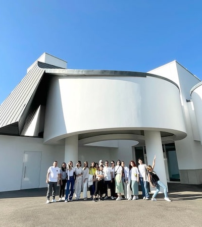 A group of people standing in front of a modern white building with a unique architectural design.