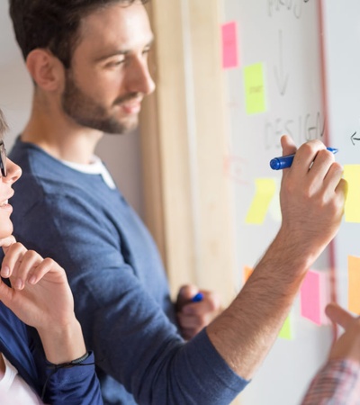 Two professionals brainstorming with sticky notes on a glass wall.