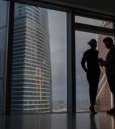 A couple is silhouetted against large urban skyscrapers.