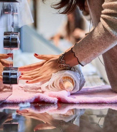 A person teaches another how to roll fabric on a table during a workshop.