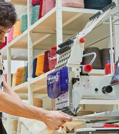 A man operating a large textile machine in a colorful fabric store.