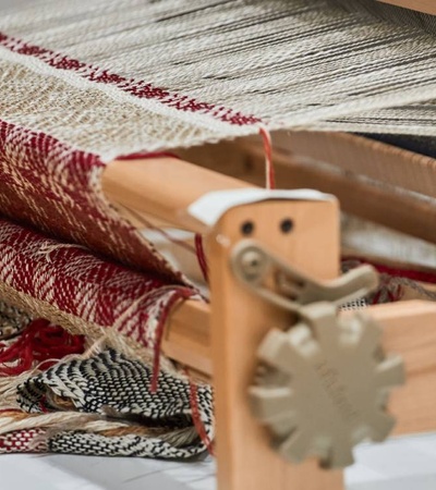 A wooden loom displaying various intricately patterned textiles.