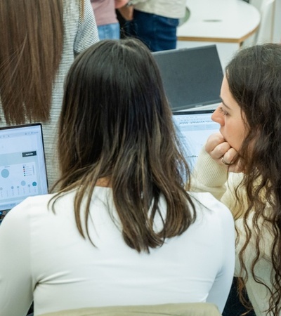 Two people are focused on a laptop screen in a collaborative setting.