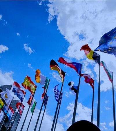 A view of multiple flags waving under a bright blue sky.
