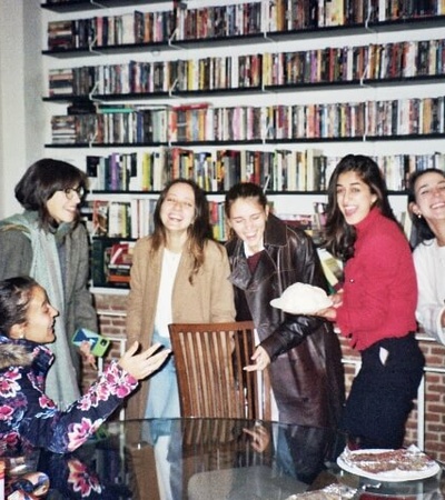 A group of young people having a joyful gathering in a room filled with bookshelves.