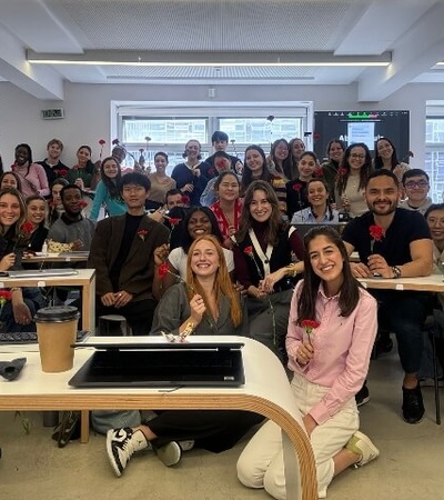 A group of diverse people smiling and posing together in a classroom or seminar setting.