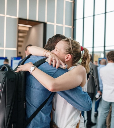A joyful reunion between two people embracing in a lively environment.