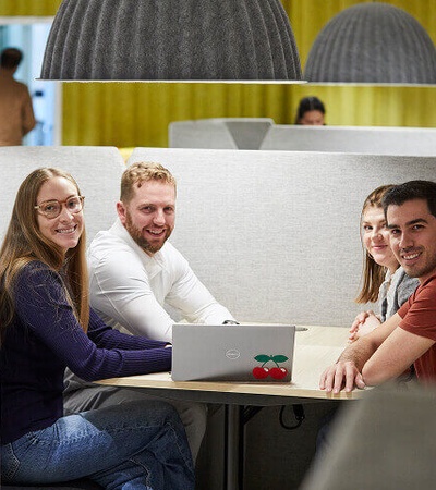 A group of four people sitting around a table in a modern office space.
