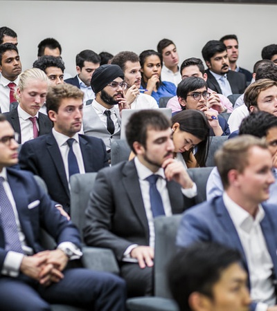 A large group of people dressed in formal suits attending a conference or seminar.
