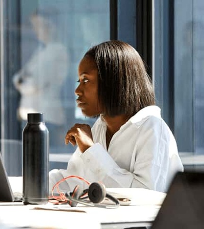 A focused woman working on a laptop in a modern office setting.