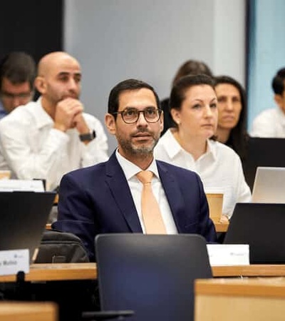 A group of professionals sitting at a conference table focusing on a presentation.