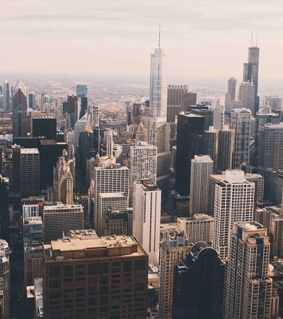 A panoramic view of a city skyline filled with tall buildings under a cloudy sky.