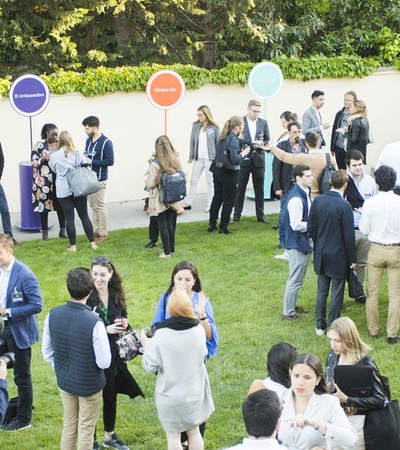A lively outdoor gathering of people networking and socializing in a green space.