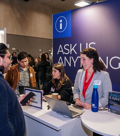 A university career fair booth with representatives engaging with visitors.