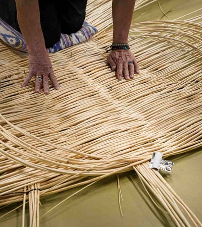 A person is weaving with long strips of material on a flat surface.