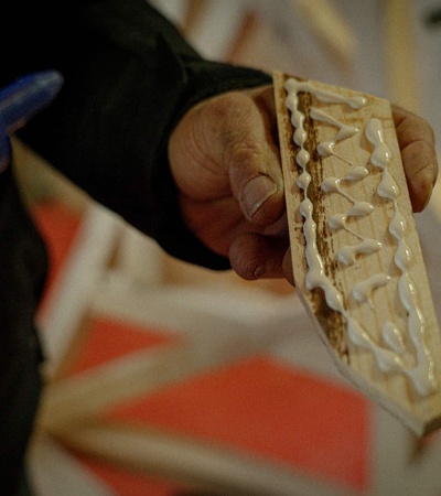 A person holding a wooden piece with glue applied to it.