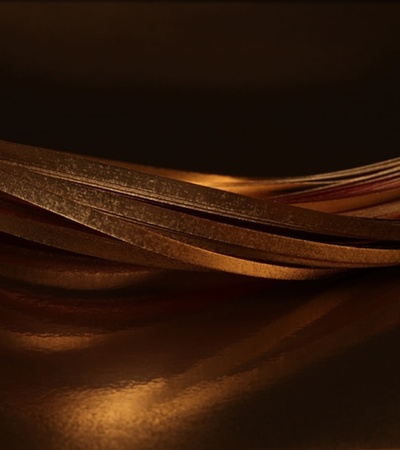 The image showcases elegant, flowing metallic strands with a rich golden hue against a dark background.