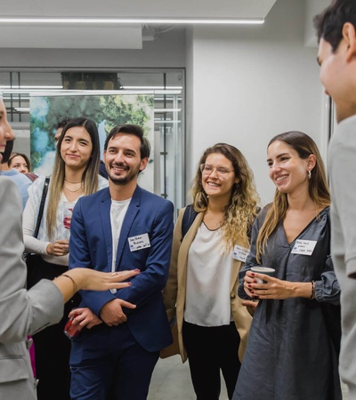 A group of young professionals engaging in a conversation during a networking event indoors.
