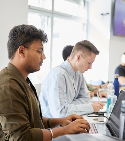 Two students are focused on their work at a modern classroom setting.