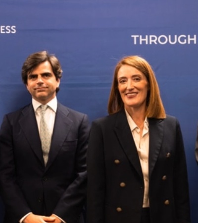 A group of four professionals standing together in front of a blue backdrop with the IE University logo.