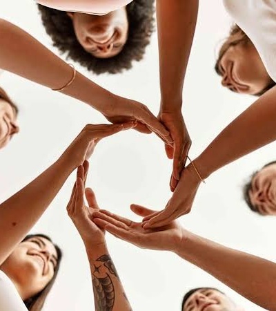 A diverse group of people forming a circle with their hands in a collaborative gesture.