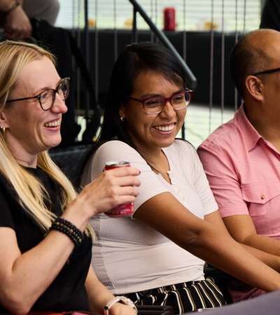 A group of three people smiling and enjoying a moment together.