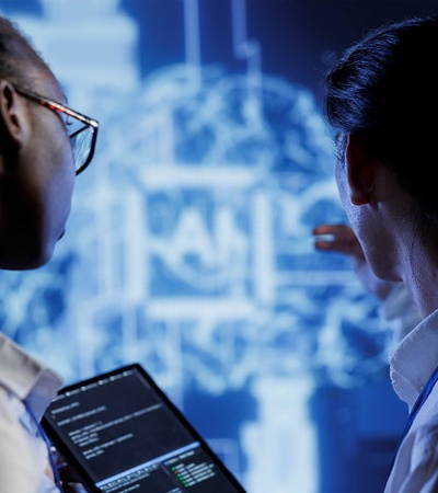 Two individuals are engaged in a discussion while looking at a digital screen displaying complex data.