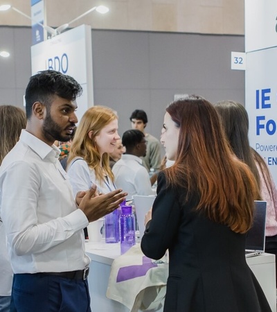 People engaging in conversation at a career forum booth with an 'Accenture' sign.