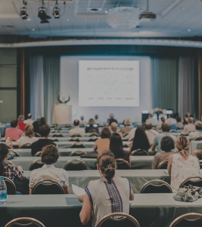 A large audience attending a presentation in a conference room.