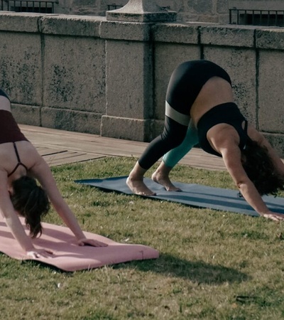 Two women practicing yoga outdoors on mats.