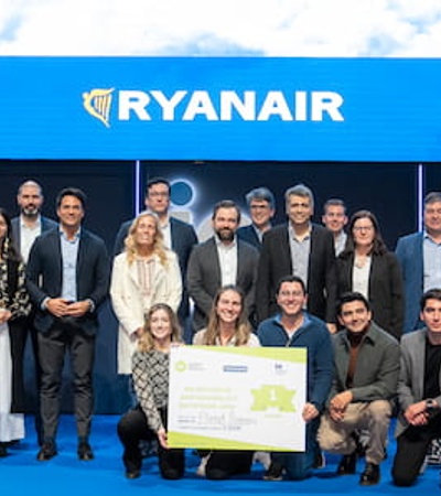 A group of people posing together with big checks at a Ryanair event in front of a banner for IE School of Science and Technology.