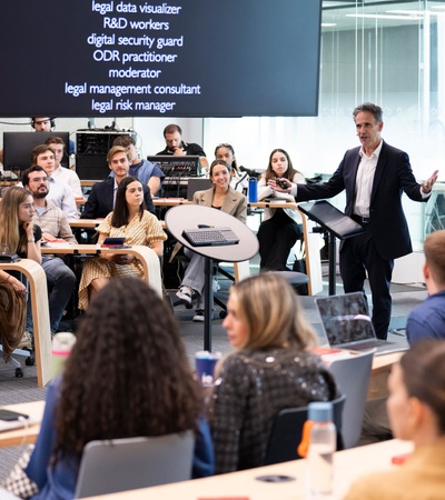 A man presenting to a group of attentive young adults in a modern seminar room.