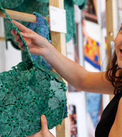 A woman smiling while pointing at a green sculpture in an art gallery.