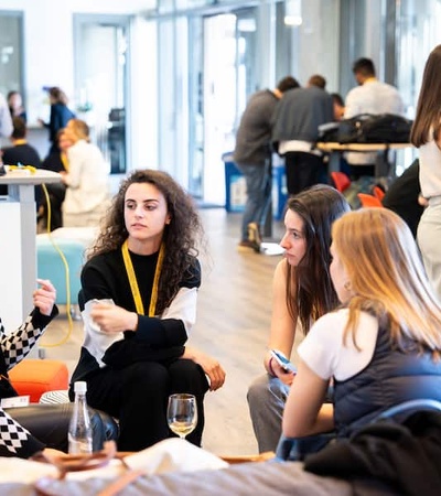 A group of women engaged in a conversation at a networking event inside a modern office space.