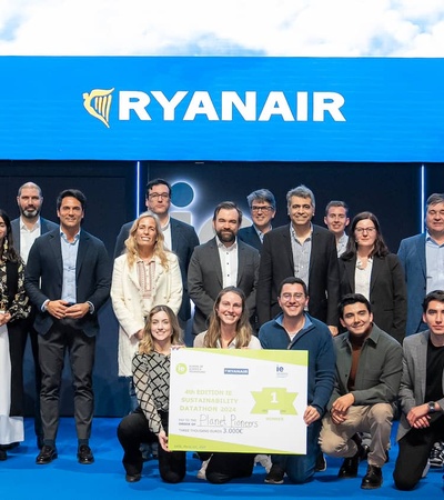 A group of people, including business professionals and students, posing with large checks at an event sponsored by Ryanair and IE University.