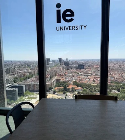 A view from a high-rise building showing a cityscape with the IE University logo in the foreground.