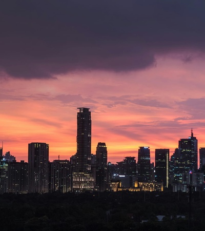 A city skyline silhouetted against a vibrant sunset.