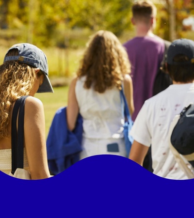 A group of young people walking through a sunny park.