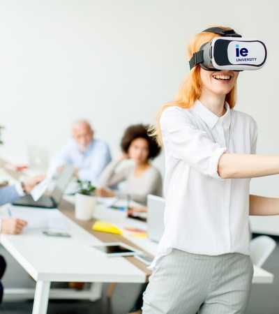 A woman wearing a VR headset is joyfully interacting in a modern office environment.