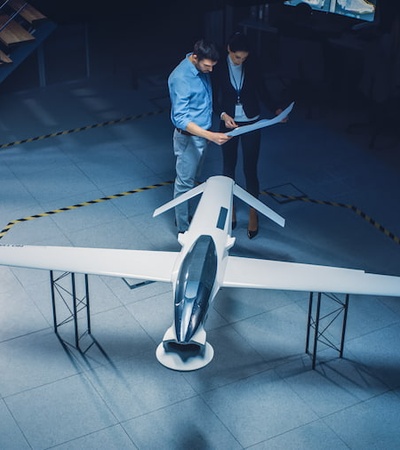 Two people inspect a model airplane in a dimly lit room.