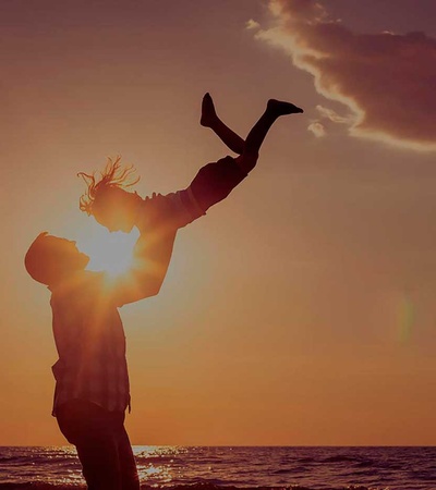 Men with a child in the beach during the sunset