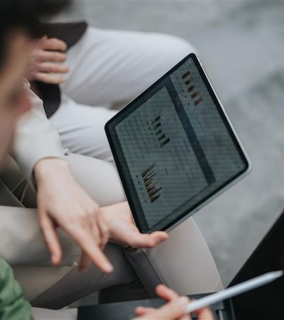 A person is analyzing data on a tablet alongside another individual.