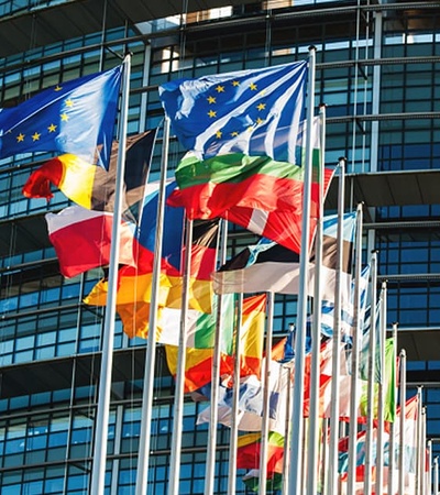 A display of various national flags in front of a modern glass building.