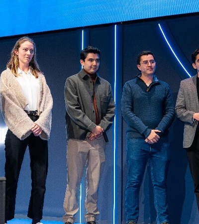 Five people standing on stage at a conference, facing the audience.