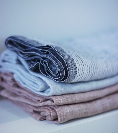 A stack of neatly folded linen fabrics in various muted colors.