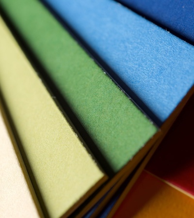 A close-up of colorful paper sheets aligned in a row, showcasing a gradient of colors from red to blue.